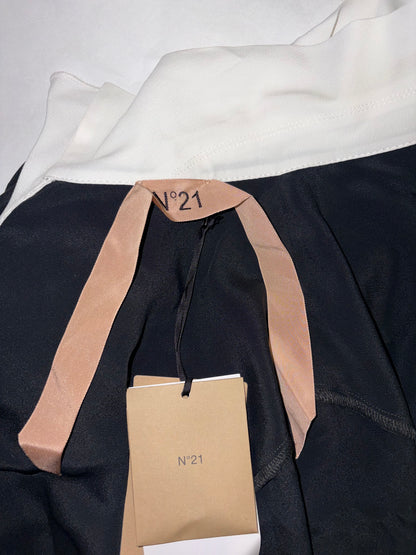 Close-up of a black garment with beige accents and a visible brand tag on a white background